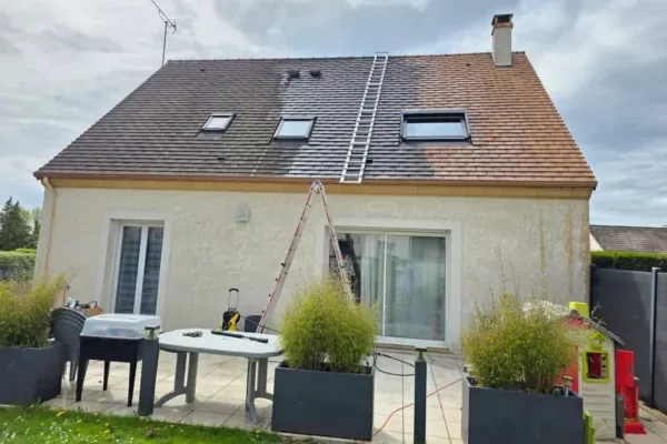 Nettoyage et démoussage de toiture en cours sur maison individuelle